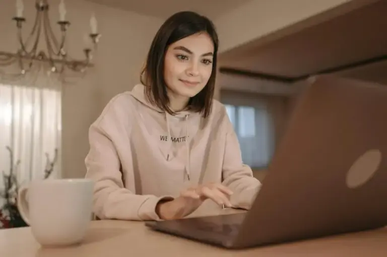 Что написать после молчания: девушка за ноутбуком обдумывает сообщение и возвращается к переписке