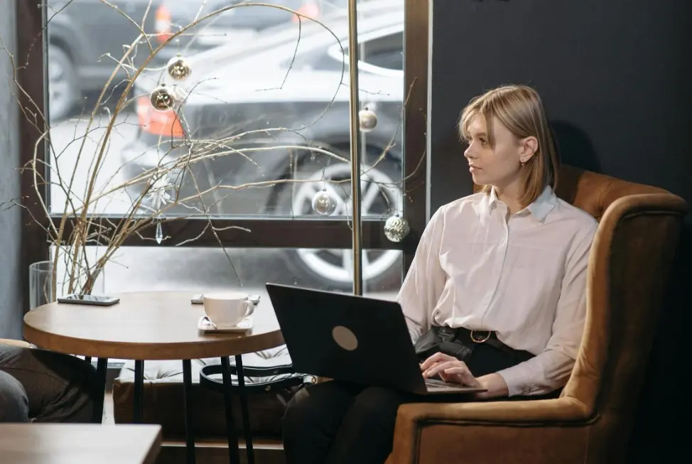 Что написать после молчания: девушка с ноутбуком в кафе обдумывает сообщение и ищет повод аккуратно возобновить переписку