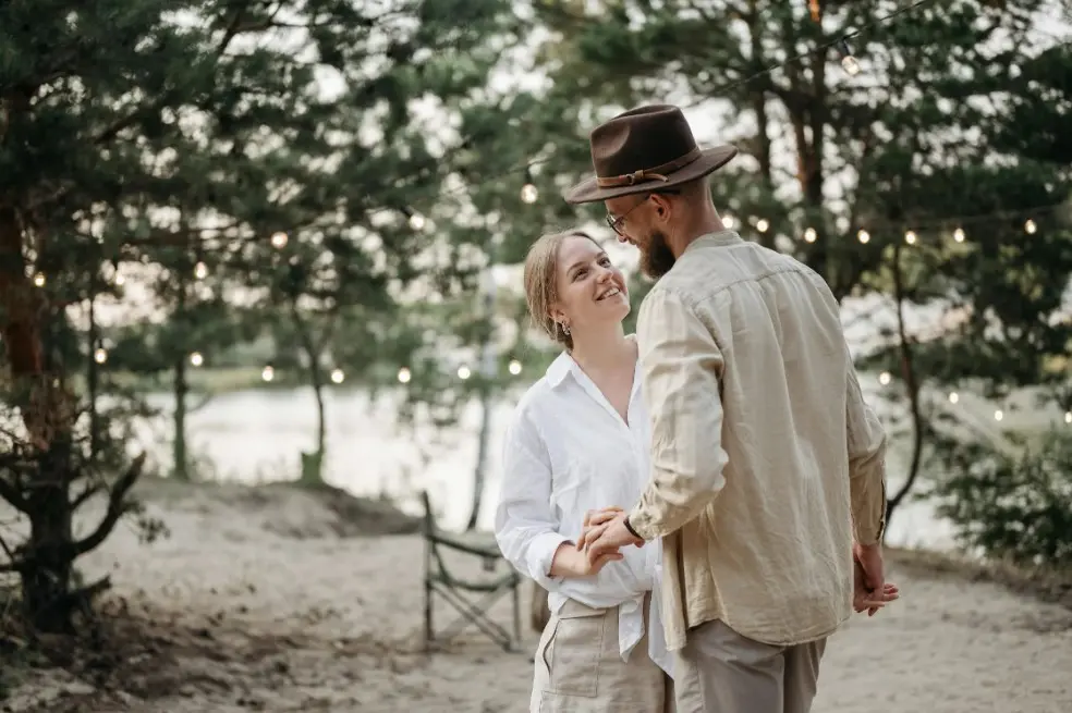 Как быть, если у влюбленных очень различный уровень доходов — пара держится за руки и улыбается на прогулке у воды