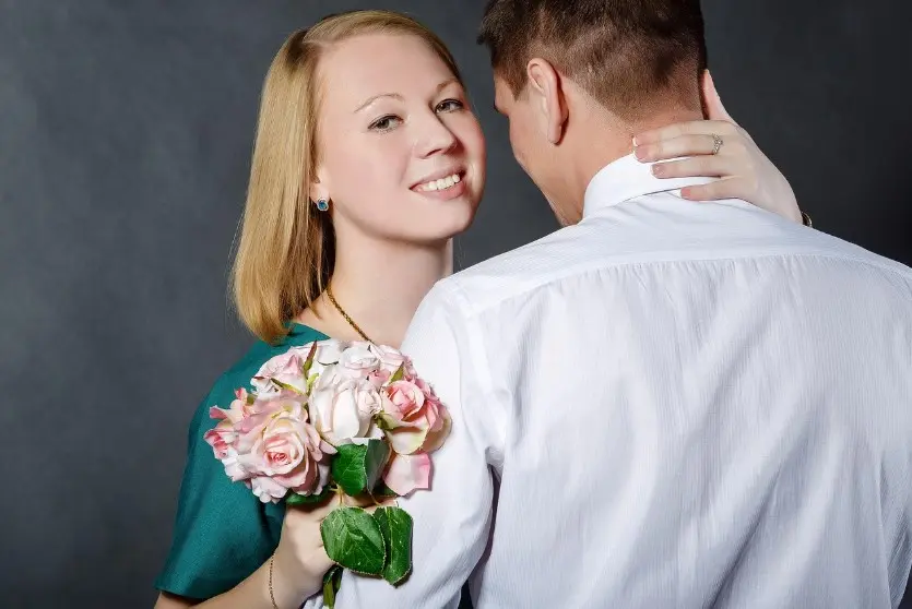 Как флиртовать без кринжа: девушка с букетом улыбается и обнимает парня