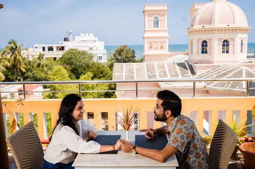 Как перейти к свиданию по переписке — парень и девушка общаются за столиком в кафе на террасе с видом на город и море.