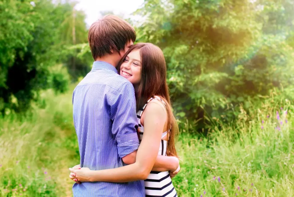 Как устанавливать границы в отношениях — влюблённая пара обнимается на природе среди зелени