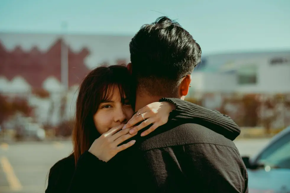 Как устанавливать границы в отношениях — девушка обнимает парня и смотрит в камеру на фоне города