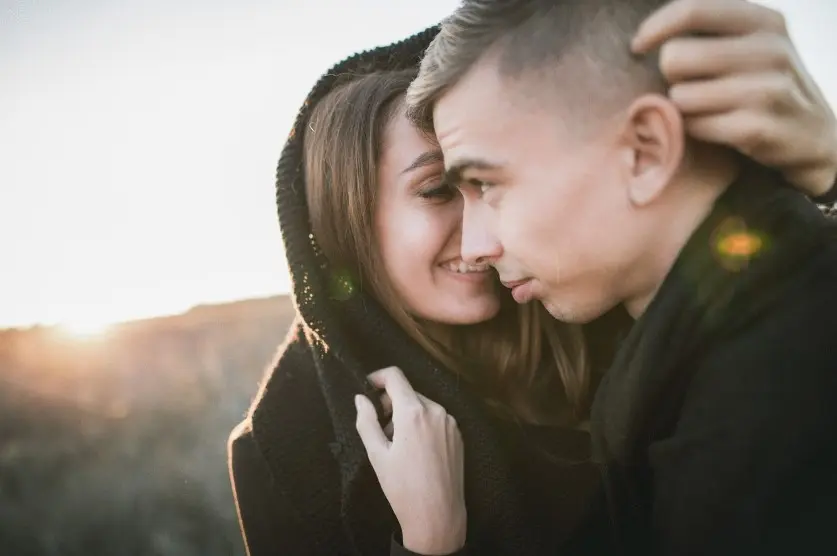 Какие темы нельзя обсуждать на первом свидании: пара обнимается на закате, крупный план, спокойная романтическая атмосфера