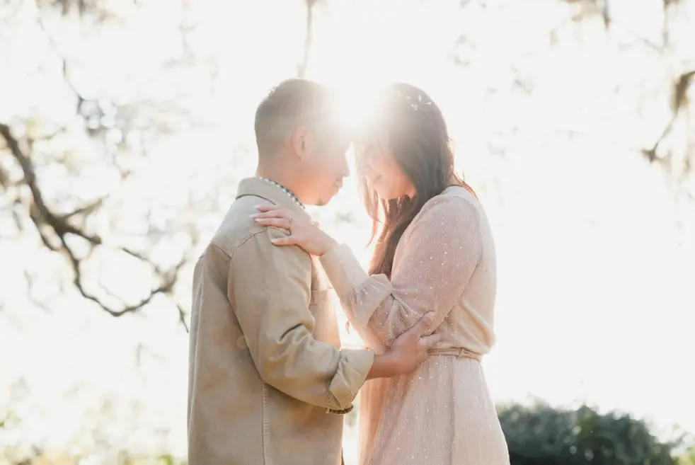 Кто за все платит в паре? Как обсуждать финансовые вопросы — влюблённая пара обнимается на улице в мягком солнечном свете.