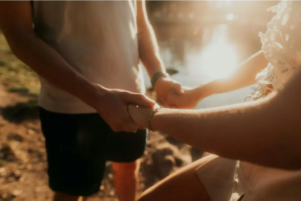 Кто за все платит в паре? Как обсуждать финансовые вопросы — крупный план: партнёры держатся за руки на закате, тёплая романтическая атмосфера.