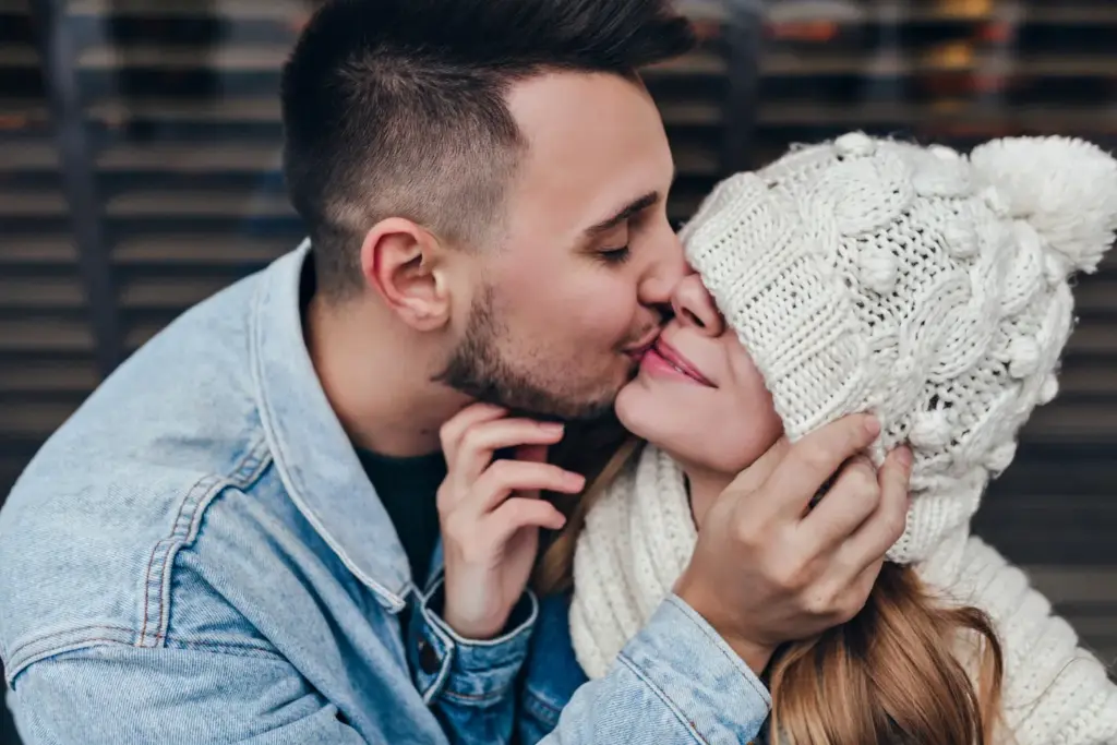 Почему иногда тянет к недоступным людям: нежный поцелуй пары зимой, момент тепла и близости в отношениях.