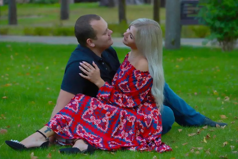 Почему писать первой — нормально: пара сидит на траве в парке и смотрит друг на друга