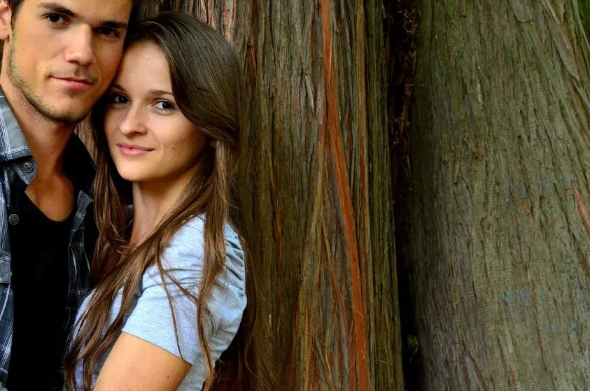 Молодая пара обнимается у дерева и задумывается, расставаться или нет с партнером